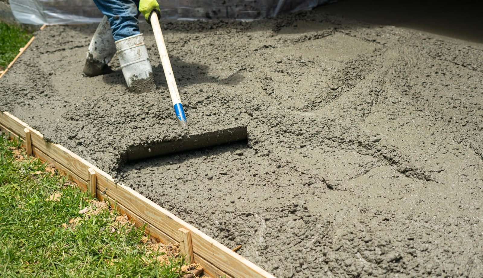 Crew spreading freshly poured concrete inside wood forms for a patio in Omaha, NE