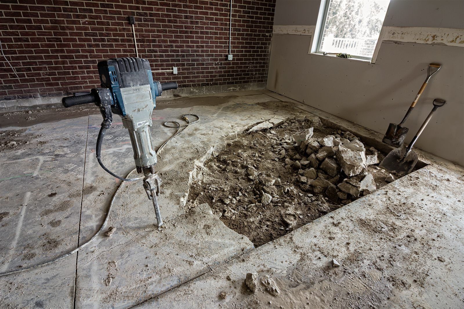 Jackhammer and broken concrete during slab removal in an Omaha, NE garage